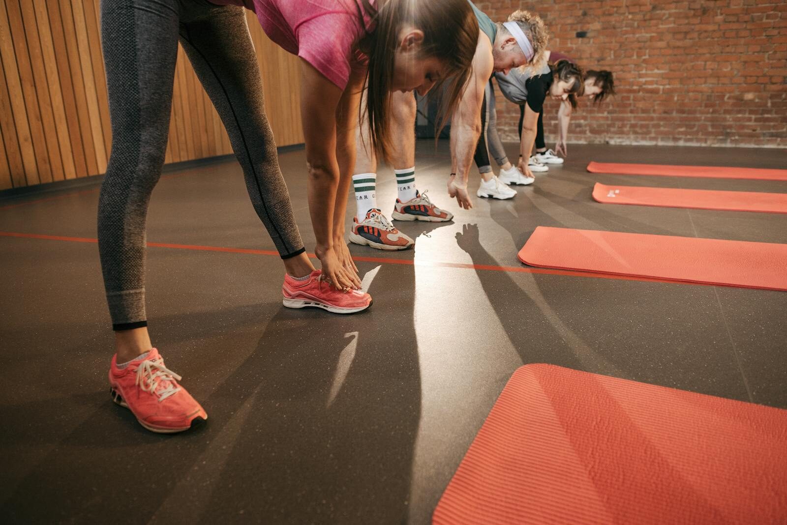 A diverse group stretches on red mats in a gym setting, enhancing fitness.